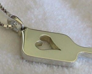 Pendentif de pickleball en forme de raquette de pickleball avec un gros coeur à l'intérieur.